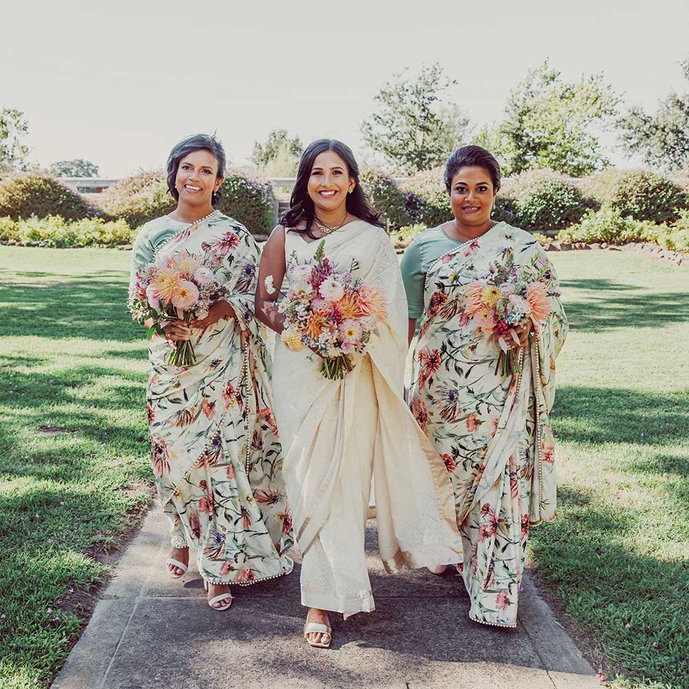 The bride and her bridesmaids walking toward the camera with smiles on their faces.