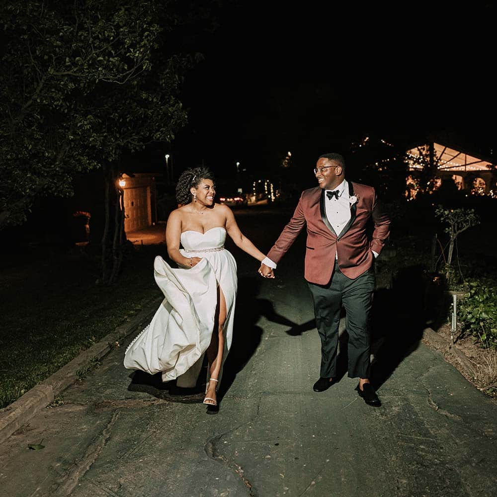 The bride and groom holding each others hands, walk away from the covered tent with smiles in their eyes at they lovingly look at each other.