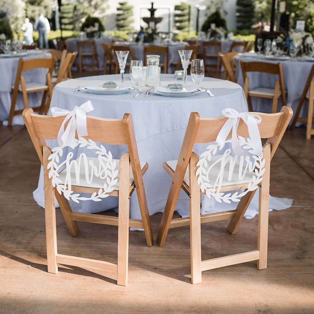 A small head table with Mr. and Mrs. sign on the back of the bride and grooms chairs looking onto the other tables set up in white linens.