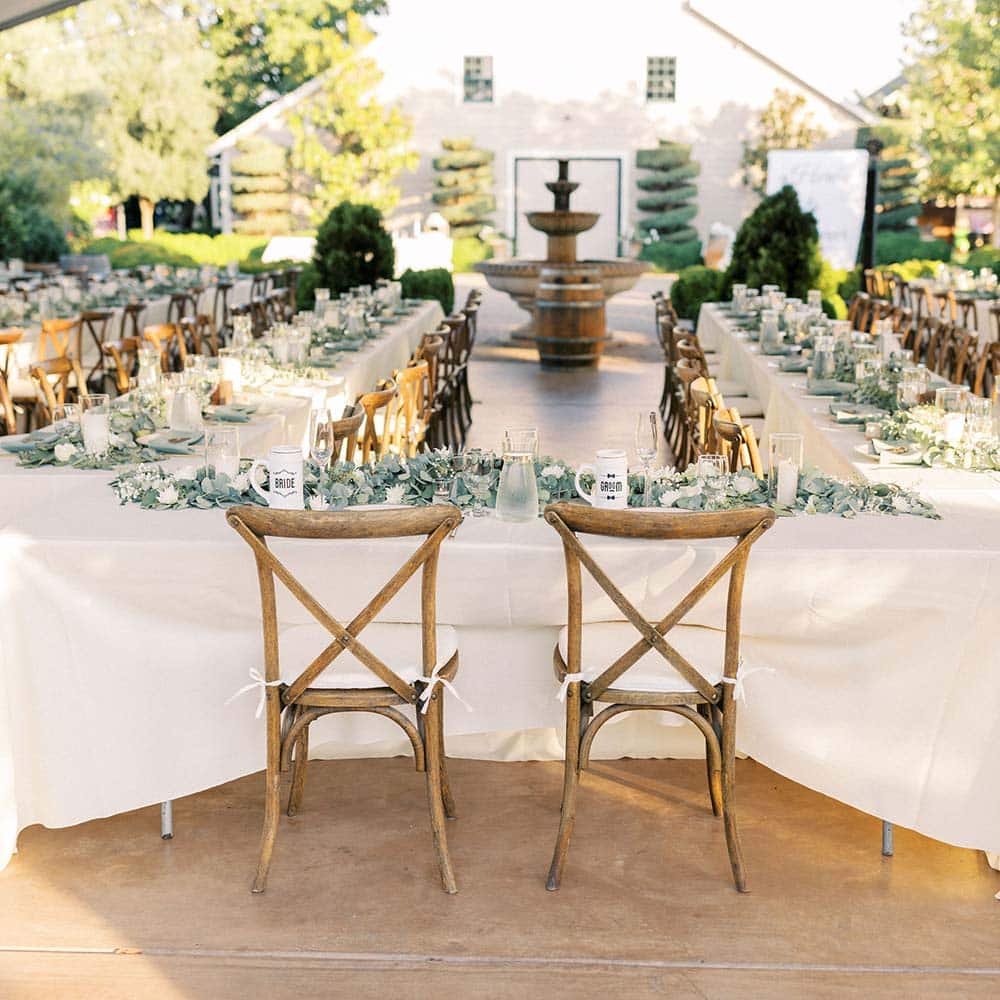Looking onto the table set up before the guests arrive seeing the 1918 barn and three tiered fountain in the distance.