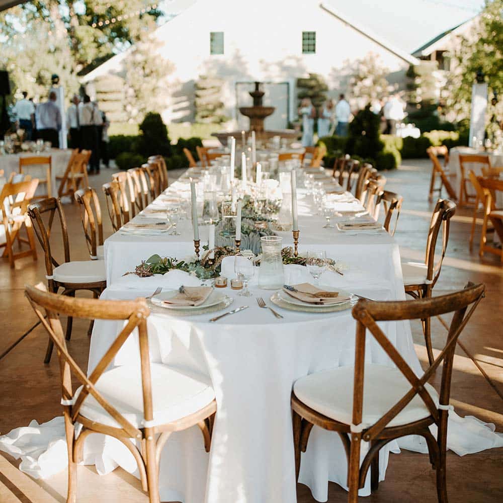 Wedding décor inspiration under a covered tent with white linens with a 1918 barn as the backdrop for this Sacramento outdoor winery wedding.