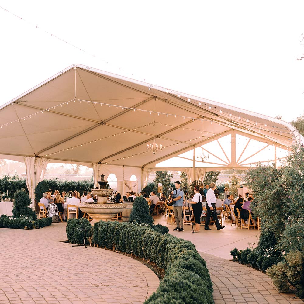 A large group enjoying time under a large outdoor tent.