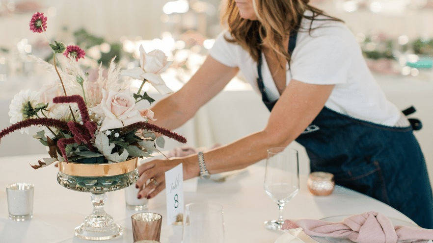 Florist arranges elegant wedding centerpiece at winery wedding