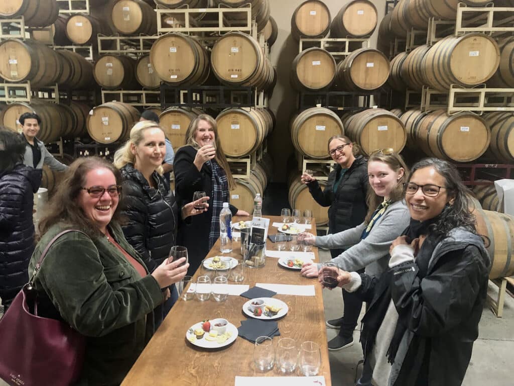 A group of girlfriends laugh as they raise glasses of Scribner Bend Tempranillo during a new wine tasting experience.